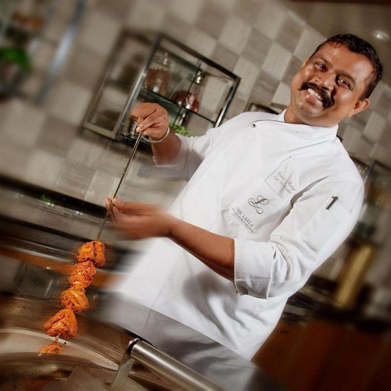 The Leela Palace Madrás Exterior foto Chef preparing chicken tikka